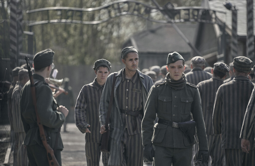 Jonah Hauer-King as Lali Sokolov seen here walking through Auschwitz with German-born actor Jonas Nay as Nazi officer Stefan Baretzki, front right. (image - Stan)